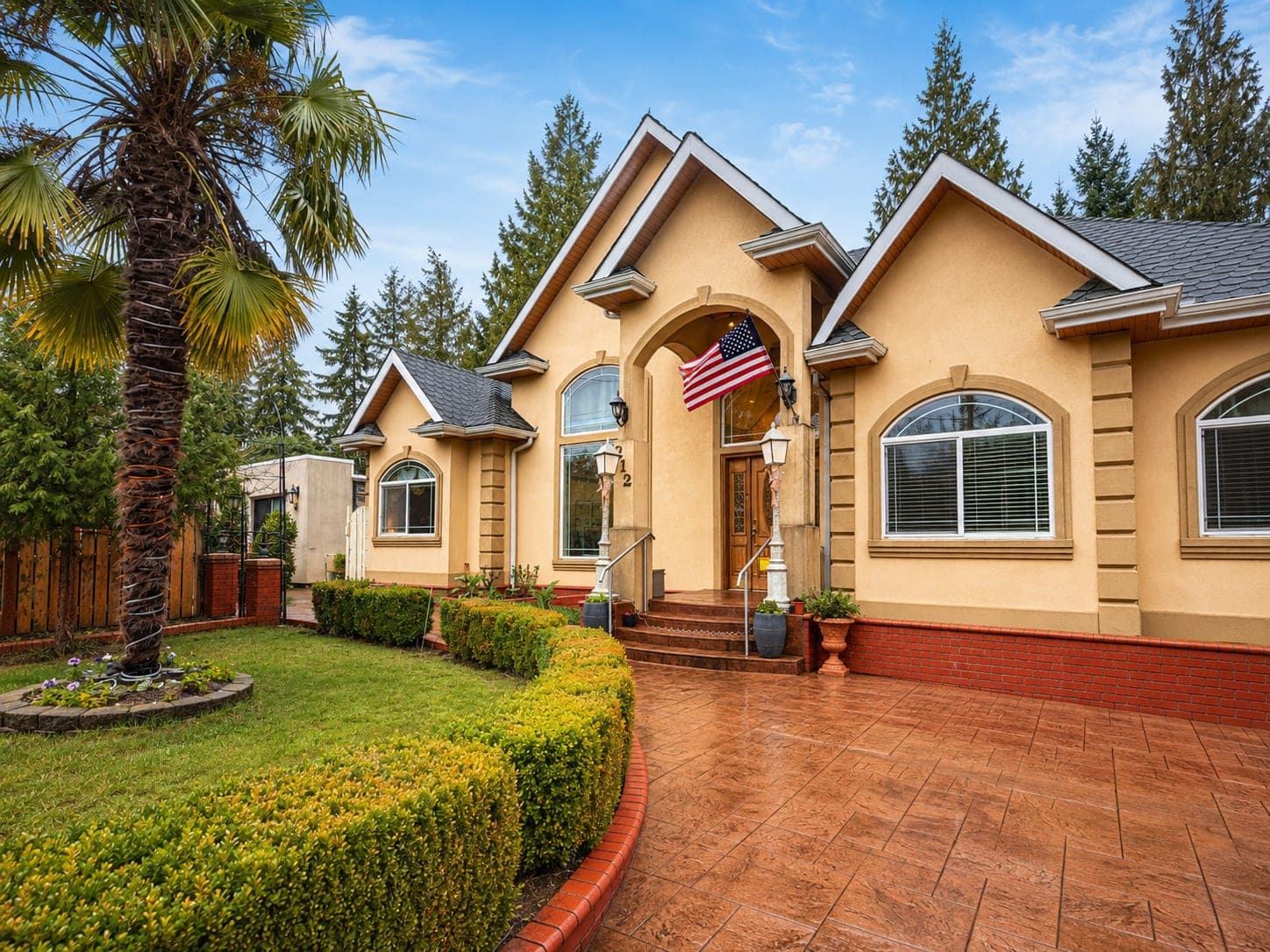 The front of Bellevue Rose — an arched entrance under gabled roofs, with clipped hedges curving along a paved driveway.
