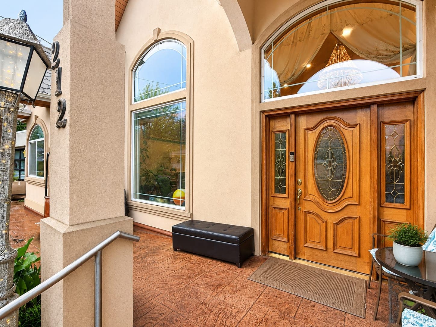 The front door of the house — a carved wooden door with a leaded oval window, set under an arched fanlight.