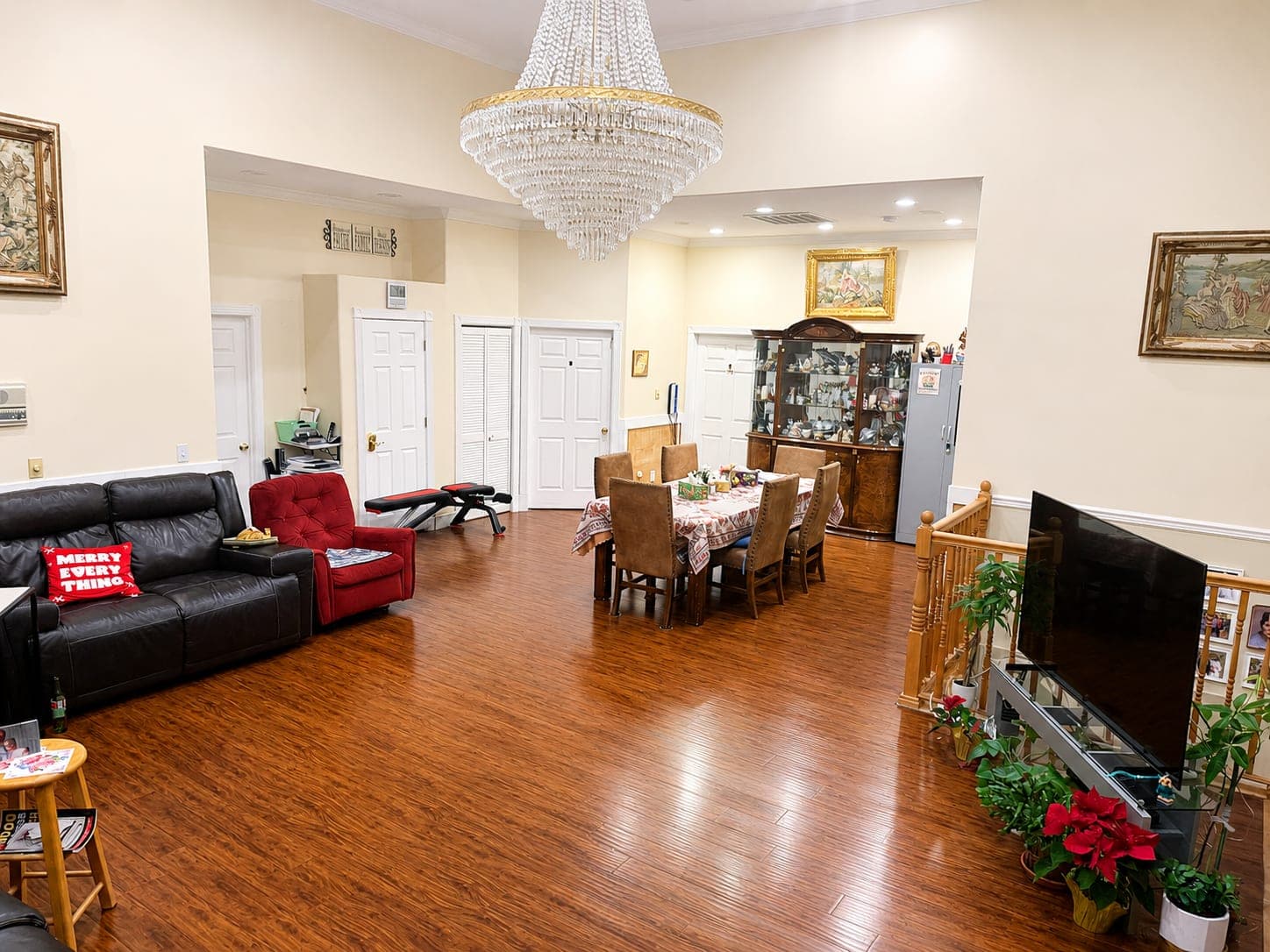 The shared living room and dining area, with sofas, a laid dining table and a chandelier over the wood floor.