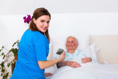 caregiver measuring senior woman's blood pressure in nursing home